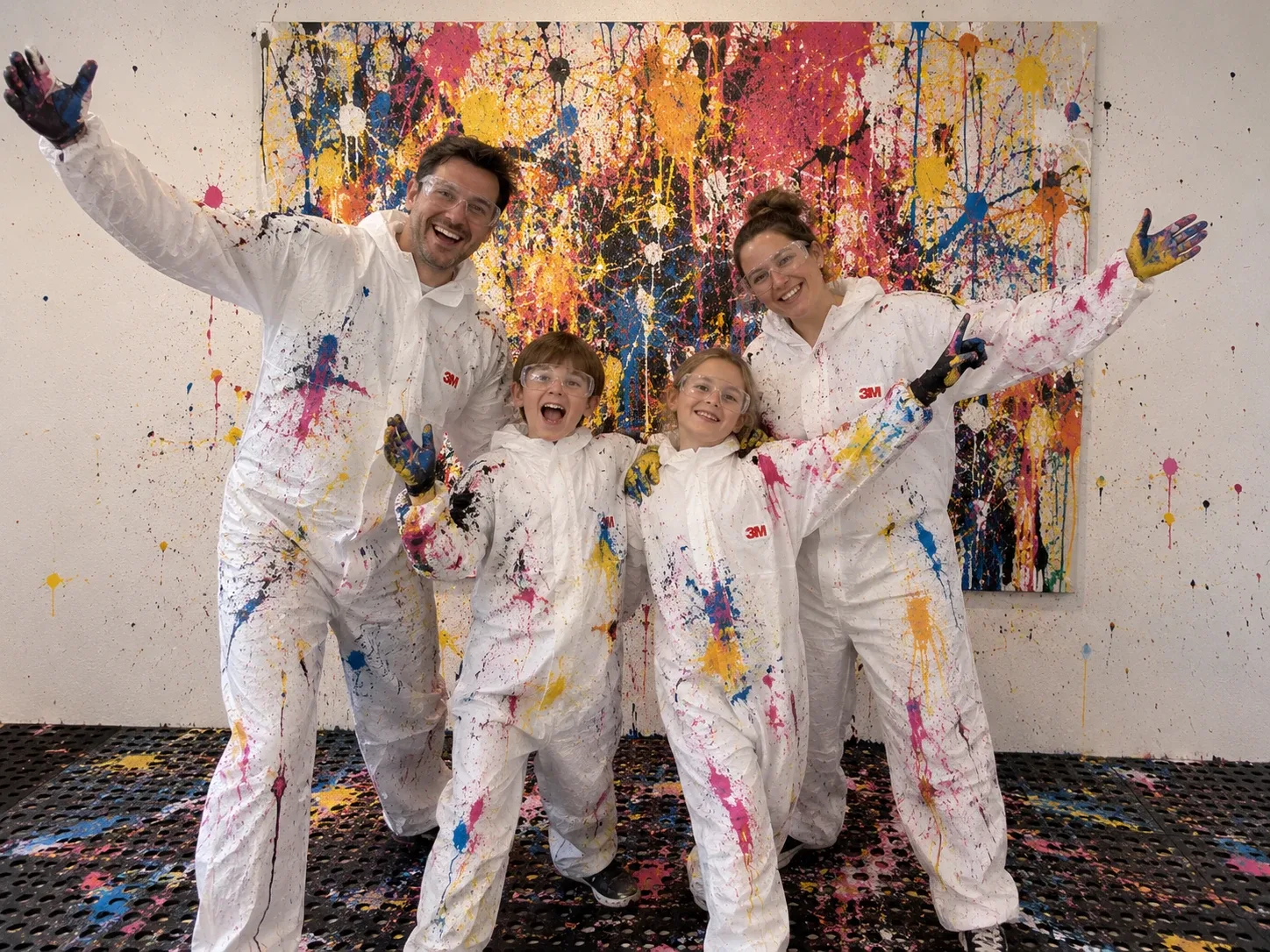 Eine Familie mit zwei Kindern präsentiert ihr farbenfrohes Action-Painting-Kunstwerk in der Art Garage bei Basel.